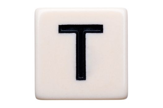 A macro shot of a game tile with the letter T on it on a white background.