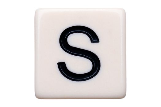 A macro shot of a game tile with the letter S on it on a white background.