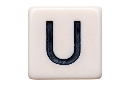 A macro shot of a game tile with the letter U on it on a white background.