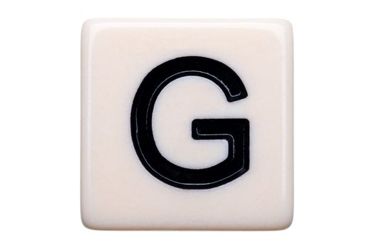 A macro shot of a game tile with the letter G on it on a white background.