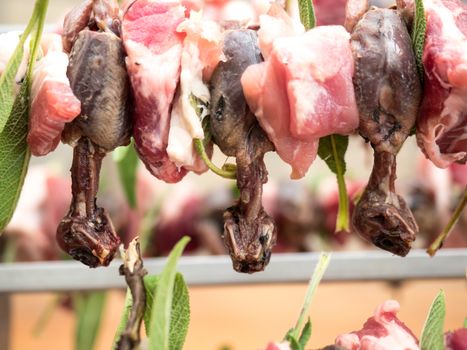 birds on the spit with meat, bacon and sage ready for roasting