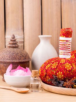 Natural Spa Ingredients herbal compress ball and essential Oil for alternative medicine and relaxation Thai Spa theme with bamboo background.