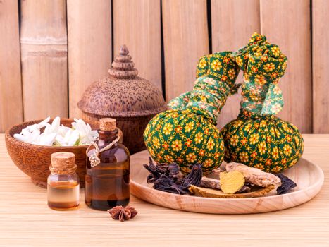 Natural Spa Ingredients herbal compress ball and essential Oil for alternative medicine and relaxation Thai Spa theme with bamboo background.