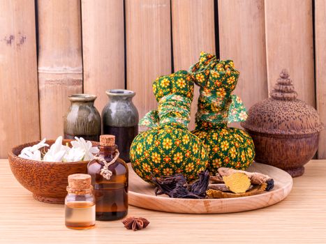 Natural Spa Ingredients herbal compress ball and essential Oil for alternative medicine and relaxation Thai Spa theme with bamboo background.