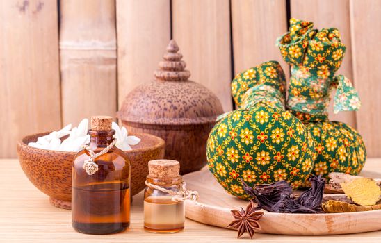 Natural Spa Ingredients herbal compress ball and essential Oil for alternative medicine and relaxation Thai Spa theme with bamboo background.