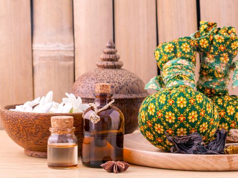 Natural Spa Ingredients herbal compress ball and essential Oil for alternative medicine and relaxation Thai Spa theme with bamboo background.