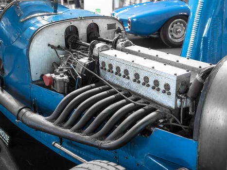 Detail of the engine and exhaust pipes of a blue vintage racing car.