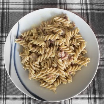 Typical Italian pasta called "fusilli" with cream and ham.