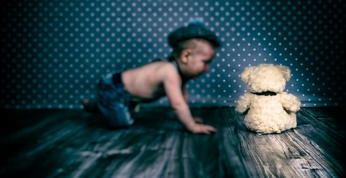 child with vintage hat and suspenders playing with teddy bear