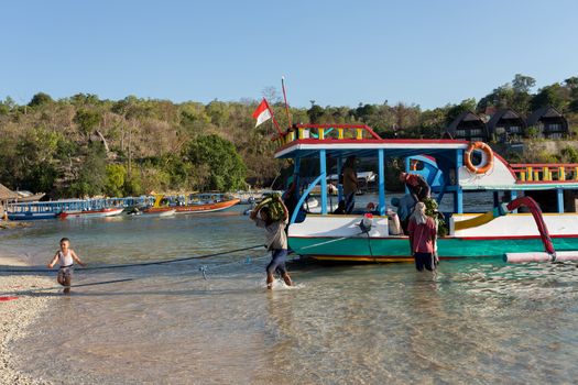 BALI, NUSA PENIDA ISLAND, INDONESIA - JULY 27.2015: Men transports cargo from ship in the hands. There is no other possibility to transport. Nusa Penida July 27. 2015 Indonesia