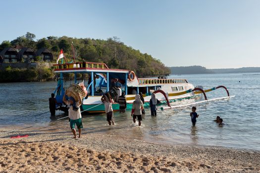 BALI, NUSA PENIDA ISLAND, INDONESIA - JULY 27.2015: Men transports cargo from ship in the hands. There is no other possibility to transport. Nusa Penida July 27. 2015 Indonesia