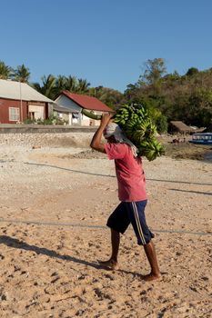 BALI, NUSA PENIDA ISLAND, INDONESIA - JULY 27.2015: Men transports cargo from ship in the hands. There is no other possibility to transport. Nusa Penida July 27. 2015 Indonesia