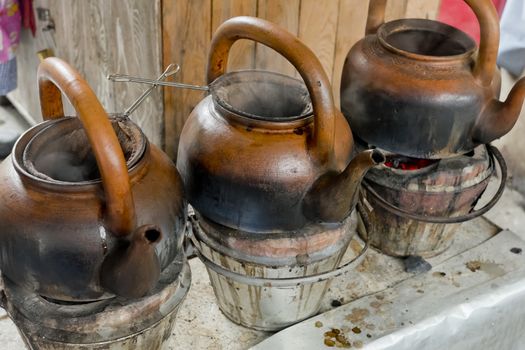 baked clay kettle with hot water on stove.