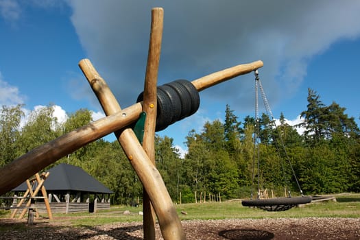 Swing made from wood poles and ropes in a nature playground                            