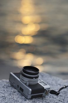 Relax with vintage camera beside sea with sunset reflected bokeh background