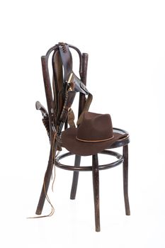 Cowboy belt, guns and hat on an old chair on isolated background