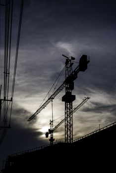 Silhouette of crane on building with sunset sky background