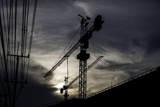 Silhouette of crane on building with sunset sky background