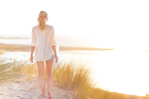 Relaxed woman enjoying freedom and life an a beautiful sandy beach.  Young lady feeling free, relaxed and happy. Concept of happiness, enjoyment and well being.  Enjoying Sun on Vacations. Copyspace.