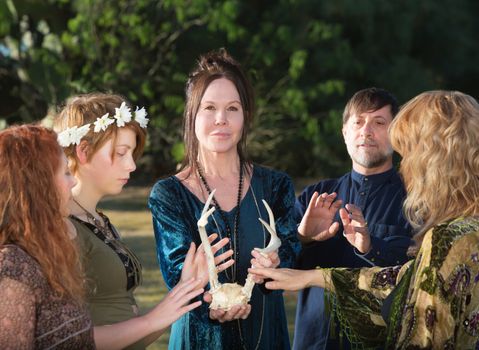 Group of adults in Wicca ceremony holding animal antlers