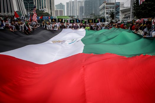 MALAYSIA, Kuala Lumpur: Demonstrators hold up a large flag during a rally in front of US Embassy in Kuala Lumpur, Malaysia on October 2, 2015. Protesters urge Americans to act against its ally Israel following clashes at Al-Aqsa mosque, between Israeli security forces and Palestinians Muslims.These pictures show hundreds of people holding signs, banners and waving flags as they parade in the Malaysian capital.