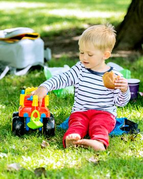 Little preschool boy playing with big toy car and having fun, outdoors.