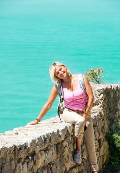 Young smiling woman sitting on stone wall
