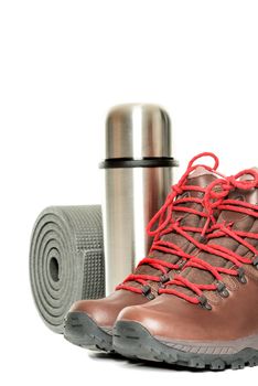 Hiker equipment: pair of mountain boots, thermo flask and sleeping mat on white background