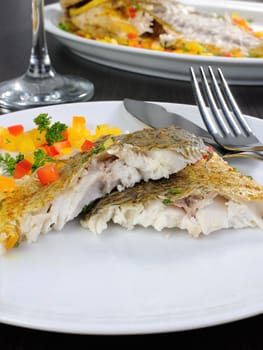 Slices of baked fish dorado with multi-colored pepper diced