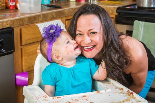 Baby girl gives her mother a kiss in the kitchen