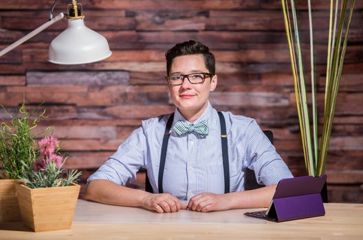 Dapper bowtie wearing woman at stylish office desk with tablet