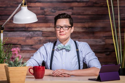 Dapper young woman at stylish office desk with a red coffee cup