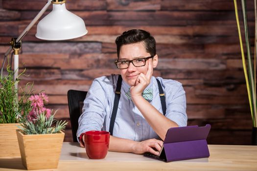 Wondering dapper female in suspenders at desk with grin