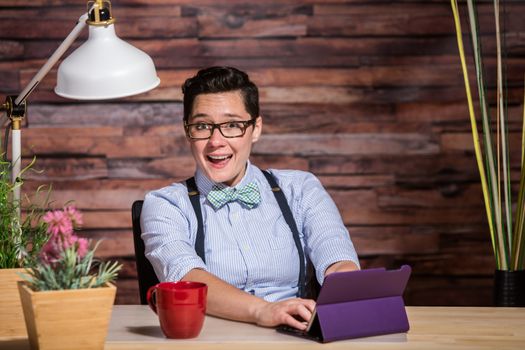 Laughing dapper woman working at desk with tablet computer