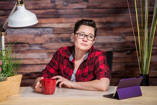 Bored woman in red shirt looking at tablet computer