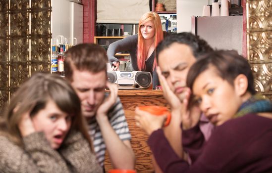 Customers covering ears while worker plays loud music