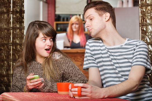 Woman holding phone as boyfriend looks over in cafe
