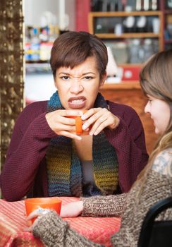 Woman with clenched teeth holding coffee mug