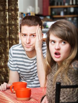 Frustrated young man sitting in cafe with woman