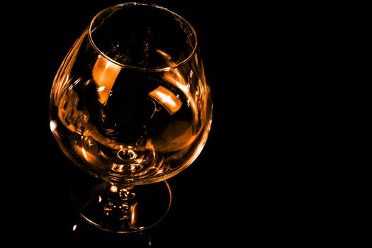 empty snifter of brandy in elegant typical cognac glass on black background with space for text