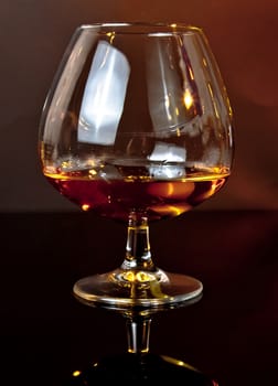 snifter of brandy in elegant typical cognac glass on dark background warm atmosphere