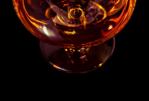 top of view of snifter of brandy in elegant typical cognac glass on black background with space for text