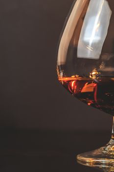 snifter of brandy in elegant typical cognac glass on dark background with space for text