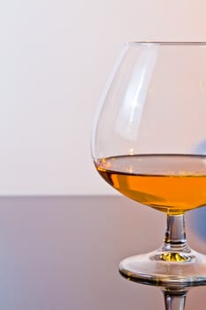 snifter of brandy in elegant typical cognac glass on light background, with space for text