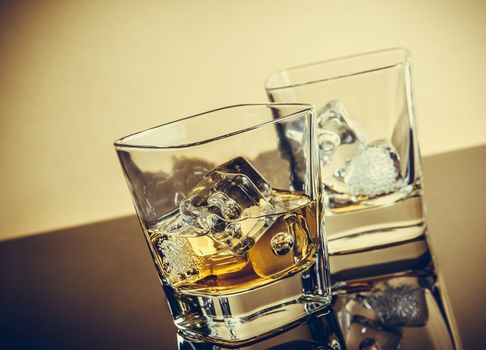 two glasses of whiskey on table with reflection, warm atmosphere, time of relax with whisky