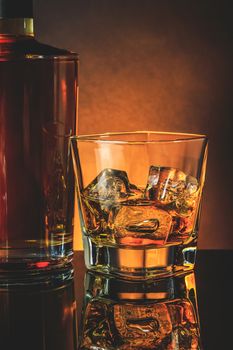 glass of whiskey near bottle on black table with reflection, warm atmosphere, time of relax with whisky
