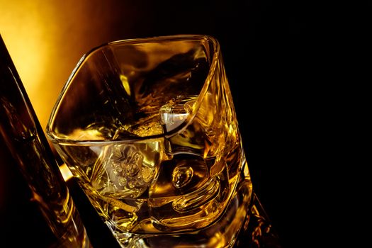 top of view of glass of whiskey near bottle on black table with reflection, warm light time of relax with whisky with space for text