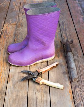 Old wooden texture background with tools and wellingtons, close up view