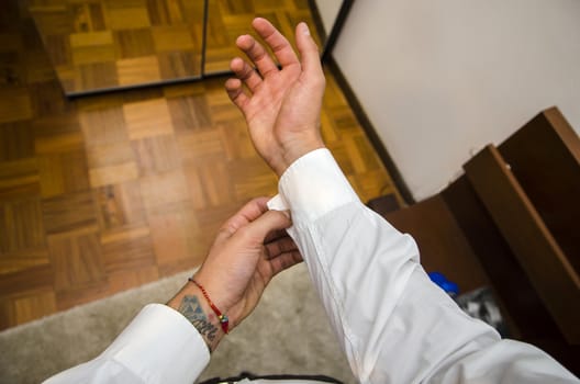 Man dressing standing in bedroom, dressing, fixing shirt cuffs, first person point of view. Self POV