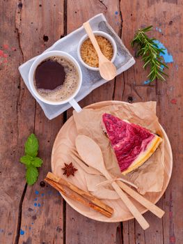 Homemade raspberry cake with cup of coffee on wooden background.